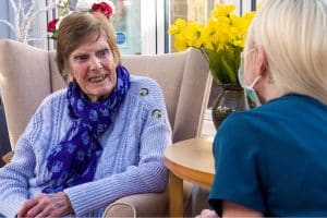 A Featherton House Care Home resident enjoying a chat with a team member in the sun room.
